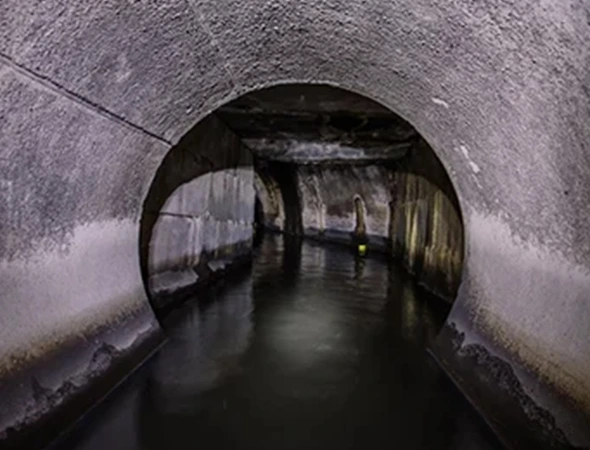 A view of a tunnel with flowing water, highlighting the ongoing sewer repairs in the area.