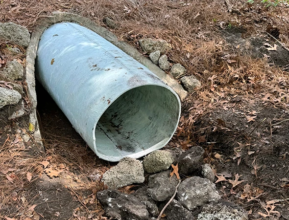 A buried pipe alongside rocks, illustrating the concept of trenchless pipe restoration techniques for underground infrastructure.
