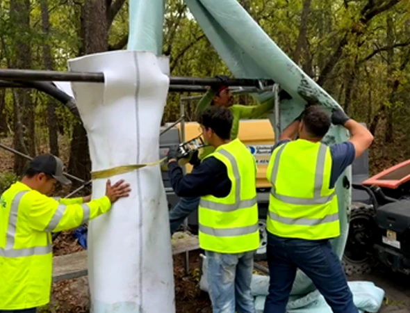 Workers are installing a large white pole as part of a trenchless plumbing project, ensuring minimal disruption to the area.